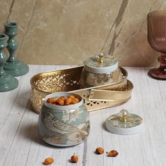 there are two bowls with nuts in them on the table next to candles and vases