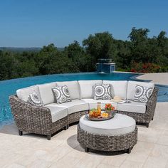 an outdoor living area with a pool in the back ground and furniture on the patio