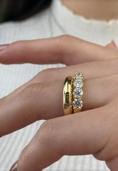 a woman's hand with a gold ring and three diamonds on the middle finger