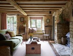 a living room filled with furniture and a fire place in front of a stone wall