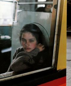 a woman looking out the window of a bus at another person walking down the street