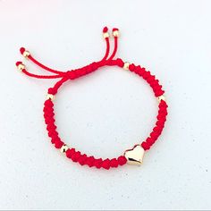 a red string bracelet with two gold heart charms on the end and a white beaded cord