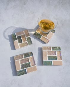 four coasters and a glass of wine on a table with white tile flooring