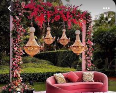 an outdoor seating area with pink couches and chandelier hanging from the ceiling