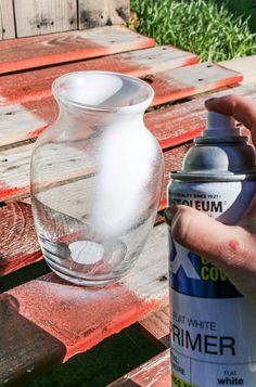 someone is spray painting a glass vase on a picnic table