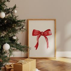 a christmas tree with presents under it in front of a framed photograph on the wall