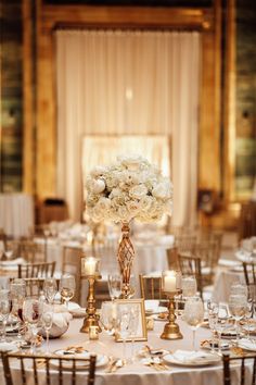 a table with white flowers and candles on it is set up for a formal function