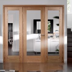 two wooden doors with mirrors on them in front of a white wall and stairs leading up to the second floor