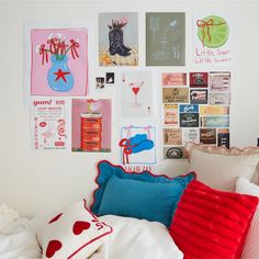 a white bed topped with lots of pillows and pictures on the wall next to it