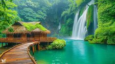 there is a wooden bridge that leads to a waterfall and some huts in the water