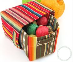 a multicolored bag filled with balls of yarn next to a ball of yarn