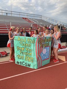 the girls are holding up a sign on the side of the track that says and the tigers beat the pinkies in the end