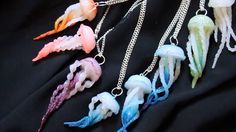 five different colored sea creatures are hanging from chains on a black surface, one is white and the other is blue