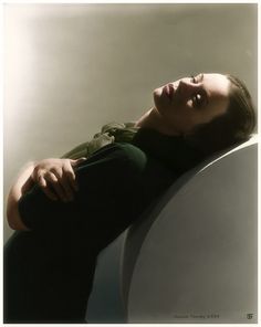 a woman laying on top of a white toilet seat next to a green shirt and black pants