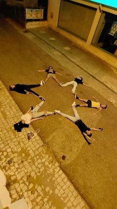 four people are laying on the ground in front of a building