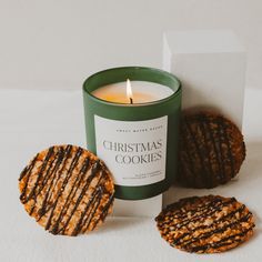 a cookie next to a candle on a white surface with a card in the background