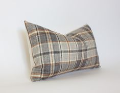 a gray and white plaid pillow sitting on top of a white table next to a wall