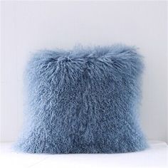 a fluffy blue pillow sitting on top of a white table