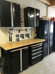 a garage with lots of black cabinets and tools on the counter top in front of it