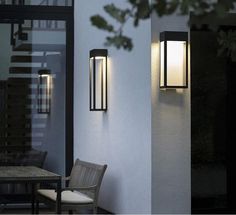 two lights on the side of a building with a table and chairs in front of it