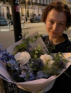 a woman holding a bouquet of flowers on the street