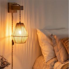 a lamp that is on the side of a bed next to a table with a bowl