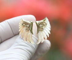 a pair of white and gold earrings with angel wings on it's ear tips