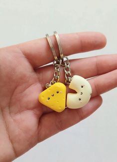 a hand holding a keychain with two pieces of cheese on it