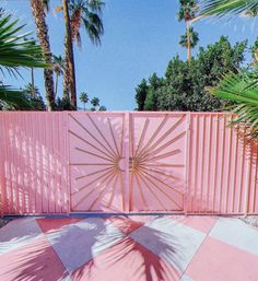 a pink gate with palm trees in the background