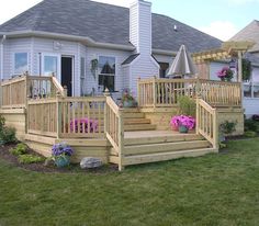 a wooden deck in front of a house with flowers and umbrellas on the balconies