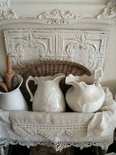 some white pitchers are sitting on a shelf in front of a basket and other items