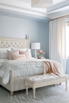 a white bed sitting next to a window with curtains on both sides and a bench in front of it