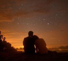 two people sitting on the ground watching the stars