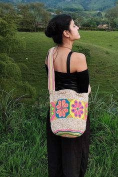 a woman is standing in the grass with her back to the camera and she has a handbag on her shoulder