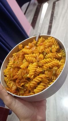 a person is holding a bowl of pasta