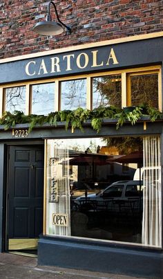 a storefront with plants in the window and an open car parked on the sidewalk