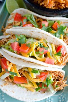 three tortillas with shredded cheese, tomatoes and cilantro on a blue plate