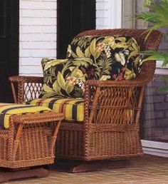 a wicker chair and footstool sitting on a patio next to a potted plant