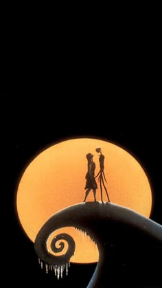 the silhouettes of two people standing in front of an orange moon