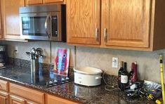 a kitchen with wooden cabinets and black granite counter tops, along with wine bottles on the counters