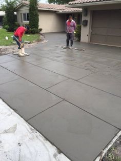 two people in front of a house that is being poured with concrete on the ground