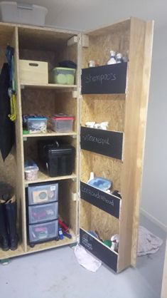 an open storage cabinet with chalkboard labels on the doors and shelves filled with items