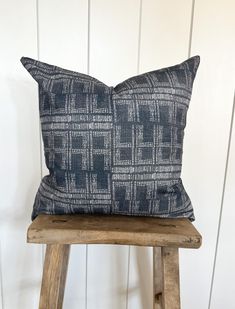 a blue and white pillow sitting on top of a wooden stool