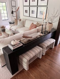 a living room with white couches and pictures on the wall above it's coffee table