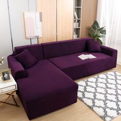 a purple couch sitting on top of a hard wood floor next to a white rug