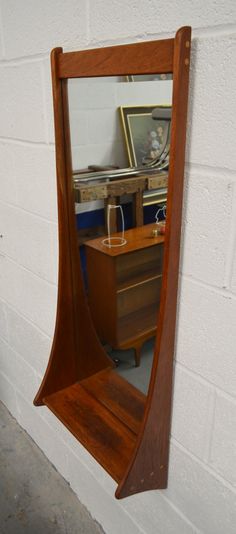 a mirror that is on the wall next to a dresser and table with a wine glass in it