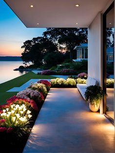 an outdoor area with flowers and plants on the side of it at night, lit up by lights