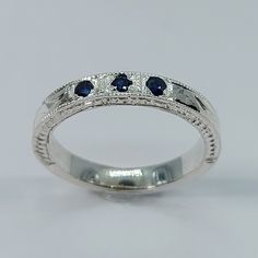 a white gold ring with three blue sapphires on the sides and two diamonds in the middle