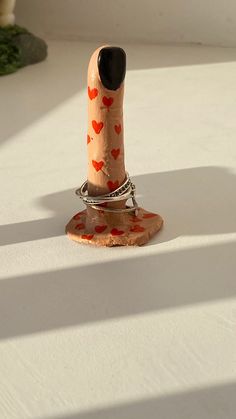 a ring is sitting on top of a small wooden object with hearts painted on it