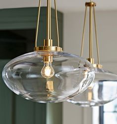 three clear glass globe lights hanging from a ceiling fixture in a room with green walls